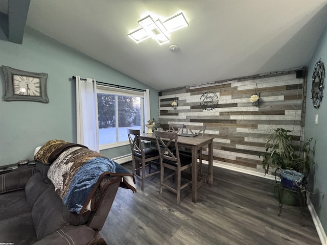 dining area featuring dark wood-type flooring, a baseboard heating unit, wooden walls, lofted ceiling, and an accent wall