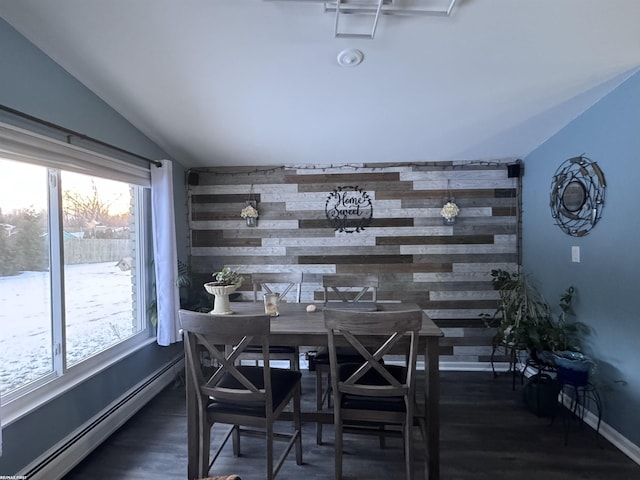 dining room featuring a baseboard heating unit, wooden walls, and an accent wall