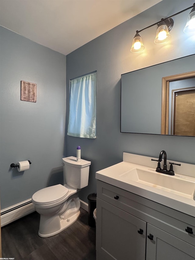 bathroom featuring baseboards, toilet, wood finished floors, vanity, and a baseboard radiator