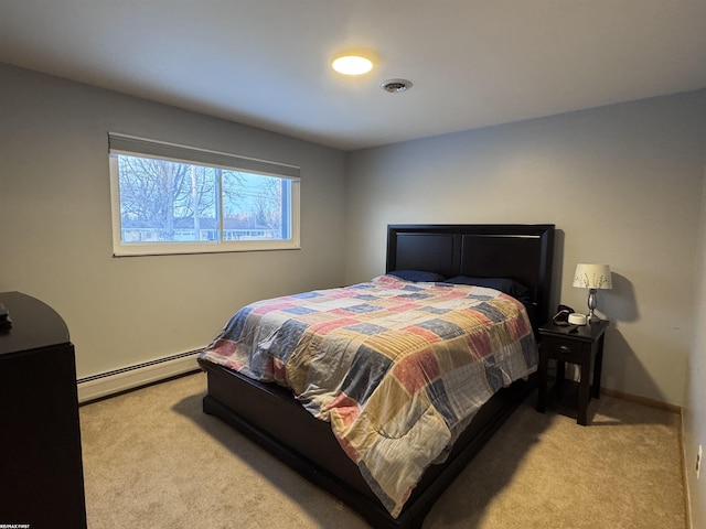 carpeted bedroom featuring a baseboard heating unit, baseboards, and visible vents