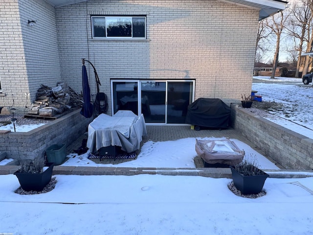 snow covered property featuring brick siding