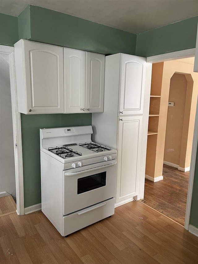 kitchen with white gas range, light wood-type flooring, and white cabinetry