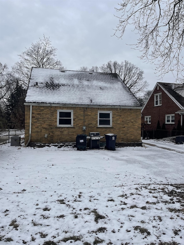 snow covered back of property featuring central AC unit