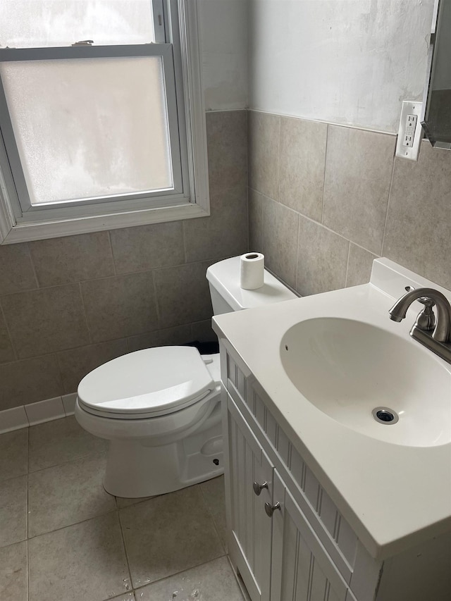 bathroom with vanity, toilet, tile patterned floors, and tile walls