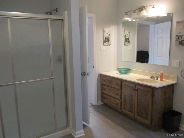 bathroom featuring a shower with shower door and vanity