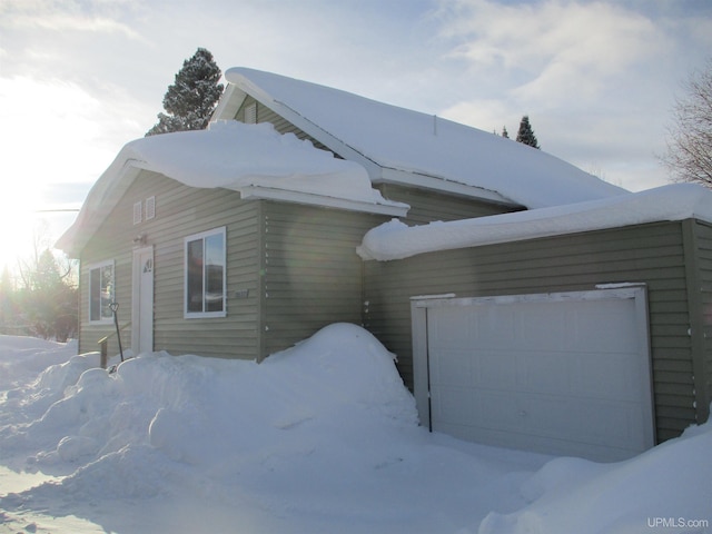 snow covered property with a garage