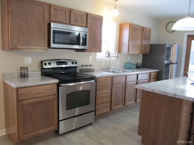 kitchen with sink, stainless steel appliances, light hardwood / wood-style floors, and pendant lighting