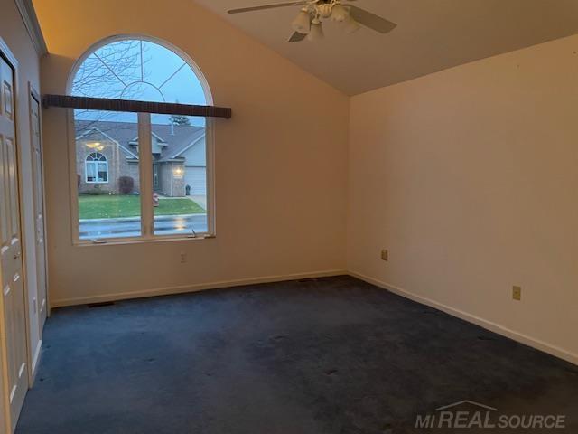 carpeted spare room with plenty of natural light, vaulted ceiling, and ceiling fan