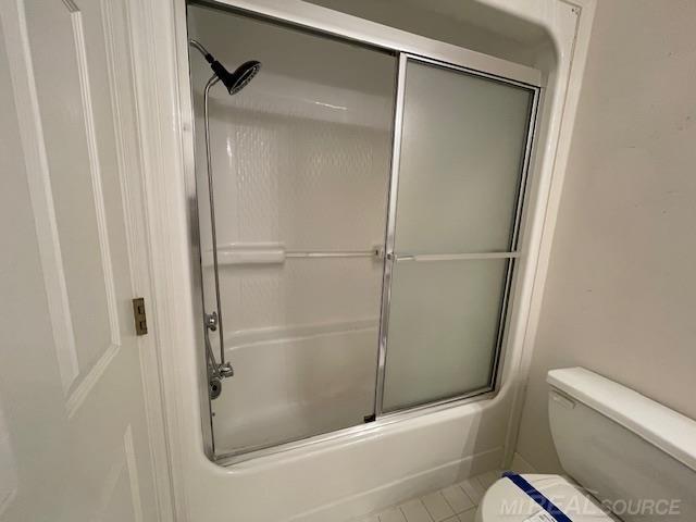 bathroom with toilet, tile patterned flooring, and shower / bath combination with glass door