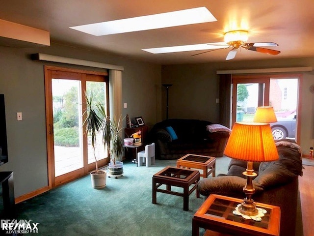 living room with carpet, plenty of natural light, ceiling fan, and a skylight