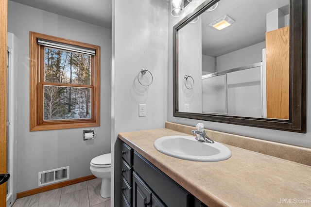 bathroom featuring vanity, toilet, and an enclosed shower