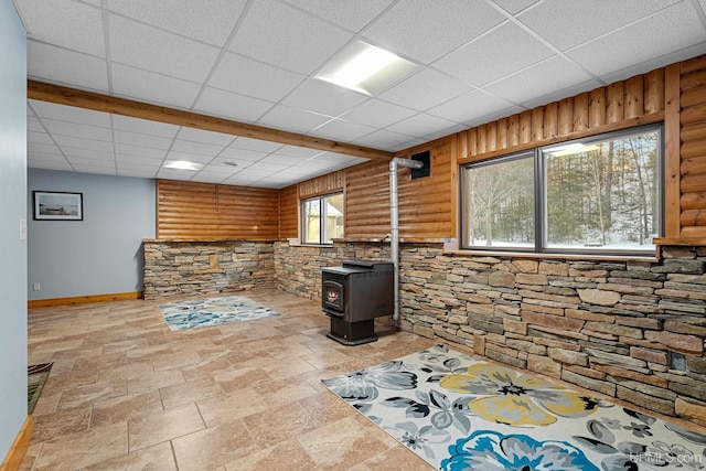 basement with a wood stove and a paneled ceiling