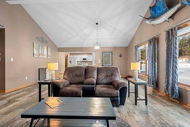 living room featuring light wood-type flooring, a notable chandelier, and lofted ceiling