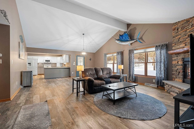 living room featuring wood-type flooring, high vaulted ceiling, beamed ceiling, and a fireplace