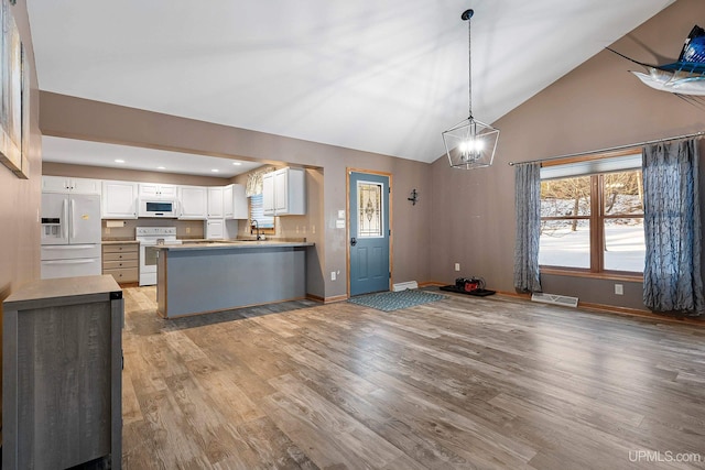 kitchen featuring white appliances, decorative light fixtures, white cabinetry, sink, and light hardwood / wood-style flooring