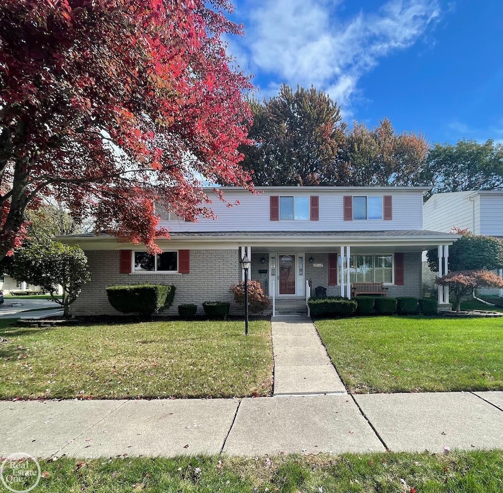 view of property with covered porch and a front yard