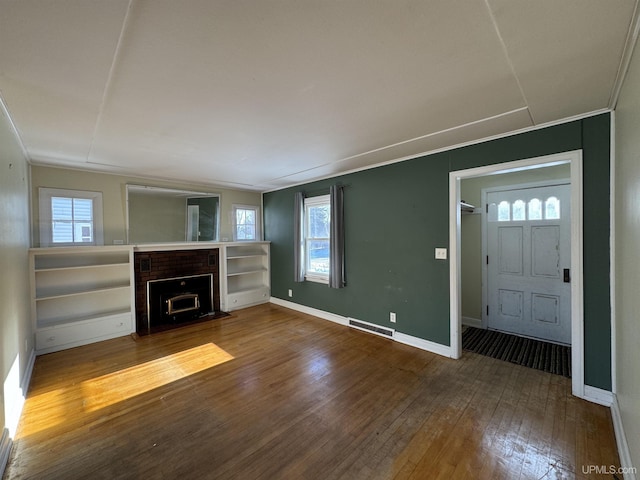 unfurnished living room with a brick fireplace, hardwood / wood-style flooring, and a wealth of natural light