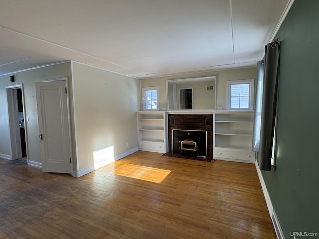 unfurnished living room with hardwood / wood-style flooring, a brick fireplace, and ornamental molding