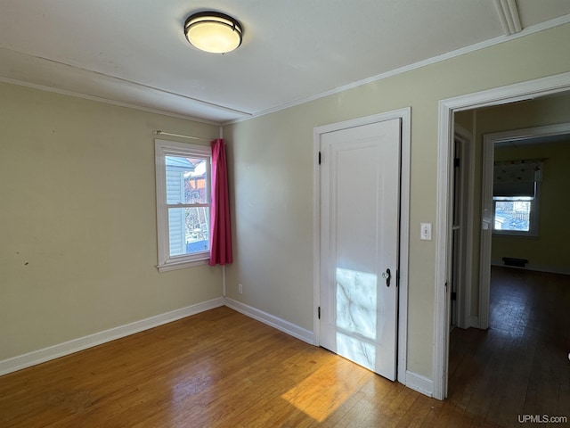 empty room with hardwood / wood-style flooring and ornamental molding