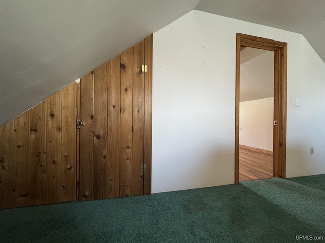 additional living space featuring wood walls, vaulted ceiling, and carpet