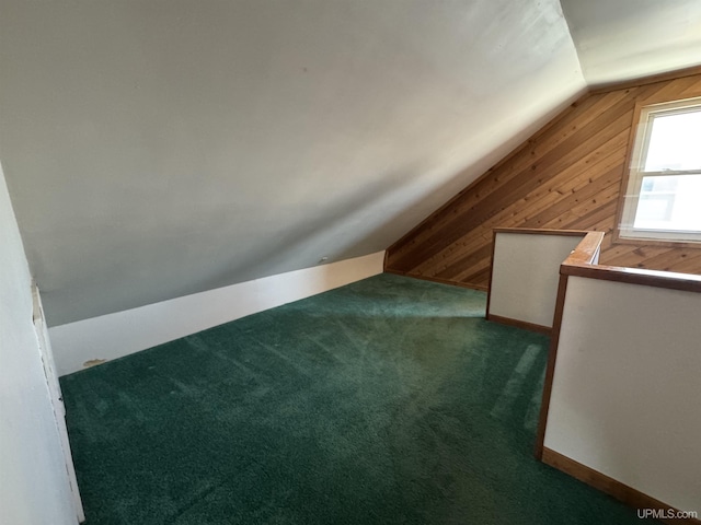 bonus room featuring vaulted ceiling, dark carpet, and wooden walls