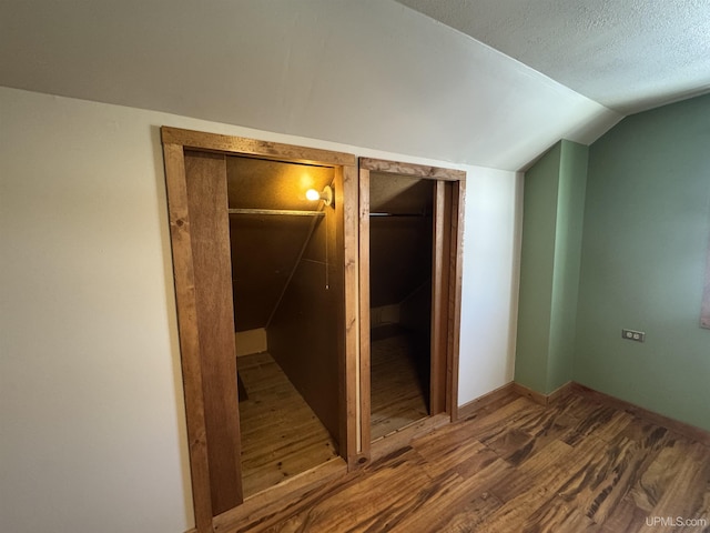 hallway featuring hardwood / wood-style flooring, a textured ceiling, and lofted ceiling