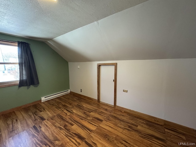 additional living space with baseboard heating, a textured ceiling, dark hardwood / wood-style flooring, and lofted ceiling