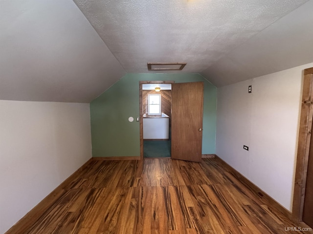 bonus room featuring a textured ceiling, dark hardwood / wood-style floors, and vaulted ceiling