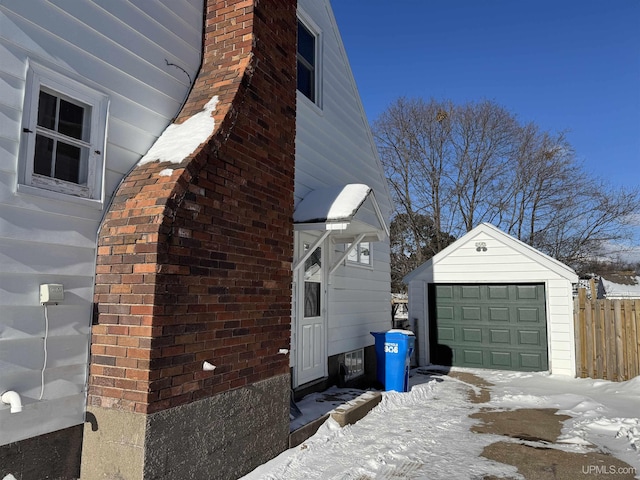 snow covered property with a garage and an outdoor structure