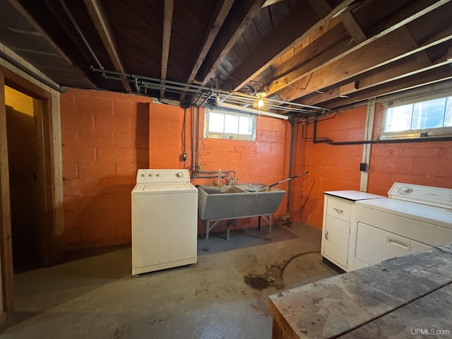 basement with sink, a healthy amount of sunlight, and washing machine and dryer