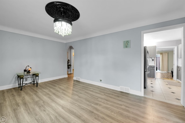 empty room featuring an inviting chandelier and light hardwood / wood-style floors