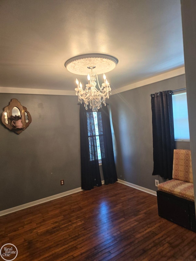 spare room featuring a chandelier and dark wood-type flooring