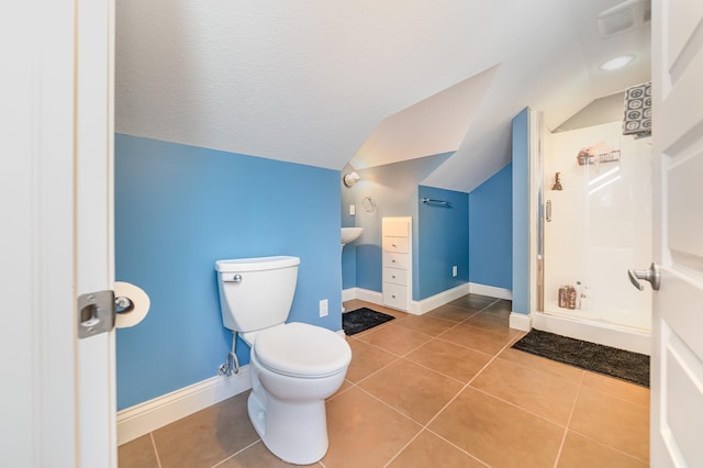 bathroom featuring a shower, tile patterned floors, toilet, and vaulted ceiling