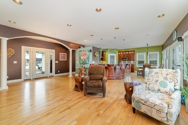 living room with light wood-type flooring and ornate columns