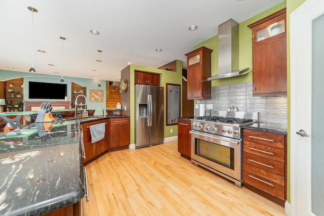 kitchen featuring tasteful backsplash, hanging light fixtures, sink, stainless steel appliances, and wall chimney exhaust hood