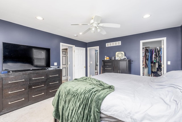 bedroom featuring light colored carpet, a closet, ceiling fan, and a walk in closet