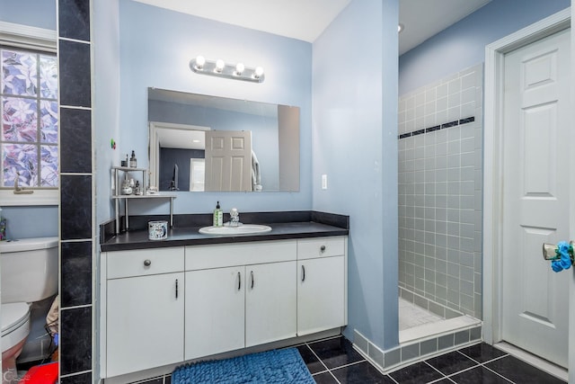 bathroom featuring a tile shower, toilet, tile patterned floors, and vanity