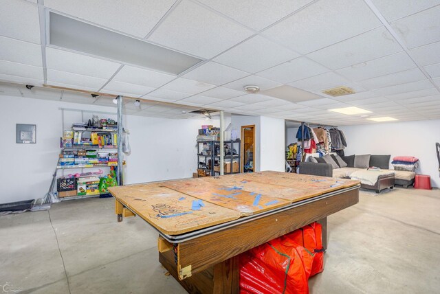 recreation room with a drop ceiling and concrete flooring