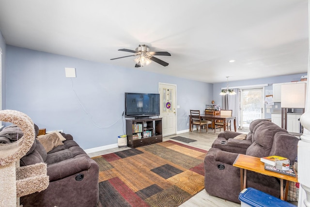 living room with ceiling fan with notable chandelier and light hardwood / wood-style floors