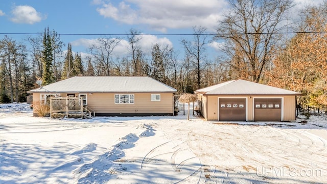 snow covered property with an outdoor structure and a garage