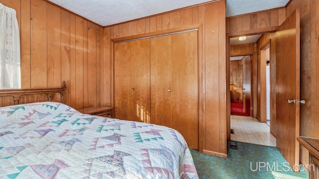 carpeted bedroom featuring wood walls, a textured ceiling, and a closet