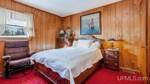 bedroom featuring dark colored carpet and wood walls