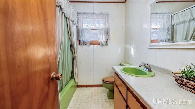 full bathroom with vanity, toilet, tile walls, and shower / bath combo with shower curtain