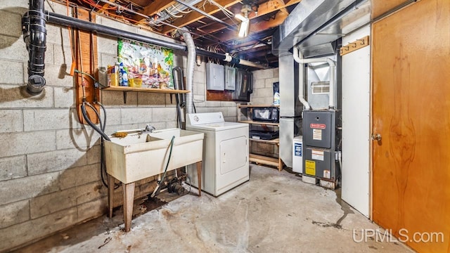 basement with sink, electric panel, heating unit, and washer / dryer