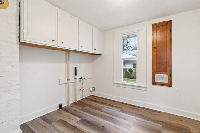 laundry room featuring light hardwood / wood-style floors, hookup for a washing machine, plenty of natural light, and cabinets