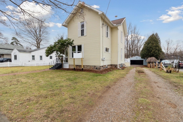 rear view of property featuring a garage, an outbuilding, and a lawn