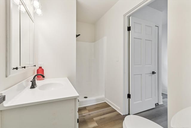 bathroom featuring hardwood / wood-style floors, toilet, walk in shower, and vanity