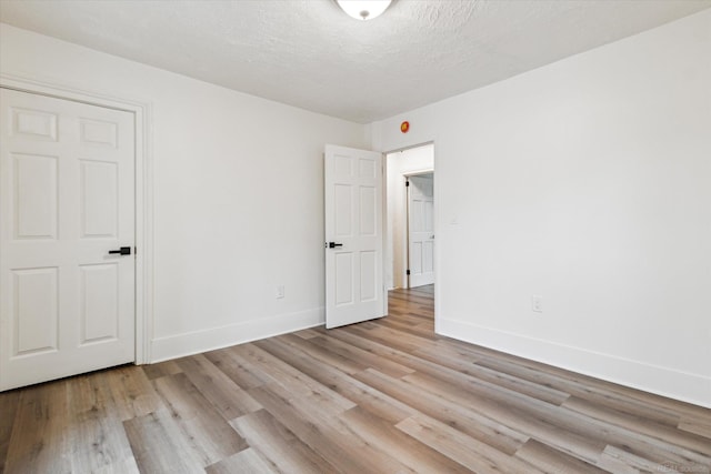 spare room featuring a textured ceiling and light wood-type flooring