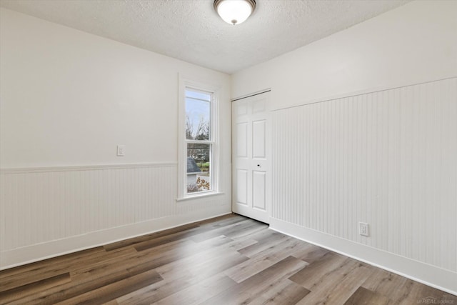 spare room featuring light hardwood / wood-style floors and a textured ceiling