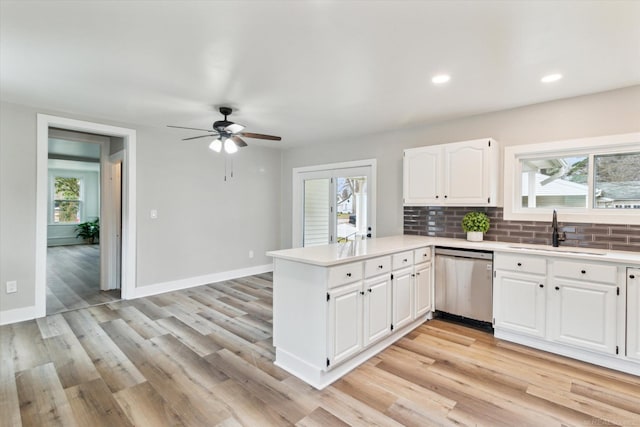 kitchen with kitchen peninsula, dishwasher, sink, white cabinets, and decorative backsplash